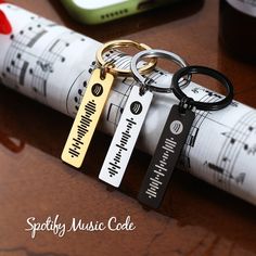 three keychains are sitting on top of a piece of music paper with musical notes in the background