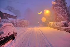 a snowy street with cars parked on the side and one car covered in snow at night