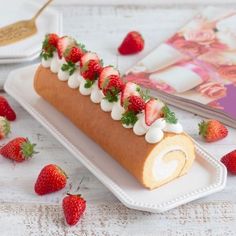 a roll with strawberries and cream on it sitting on a plate next to a book