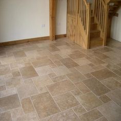 an empty room with stairs and tile flooring on the ground in front of a wooden banister