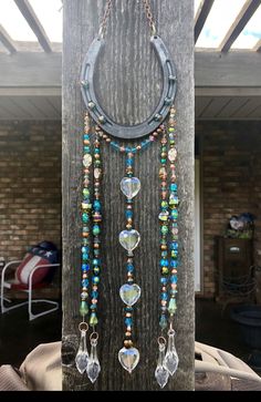 a piece of jewelry is hanging on a wooden post with beads and chains attached to it