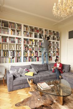 a living room filled with furniture and bookshelves covered in lots of bookcases