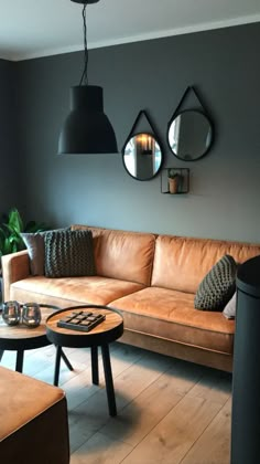 a living room with brown leather couches and round mirrors on the wall above them