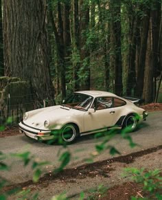 an old car is parked on the side of the road in front of some trees