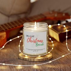 a candle sitting on top of a wooden table next to a string of christmas lights