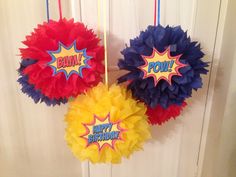 three red, yellow and blue paper pom - poms hanging from a door