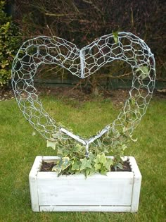 a heart shaped wire sculpture sitting on top of a white planter