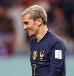 a close up of a soccer player wearing a blue uniform and smiling at the camera