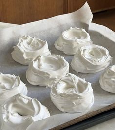 some white frosted cupcakes sitting on top of a pan