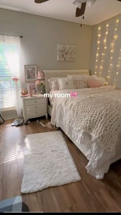 a bedroom with white bedding and lights on the wall above the bed is shown in this image