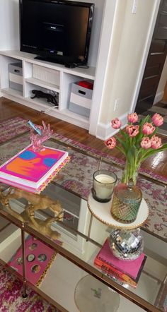 a living room with a glass coffee table and pink flowers on the top of it