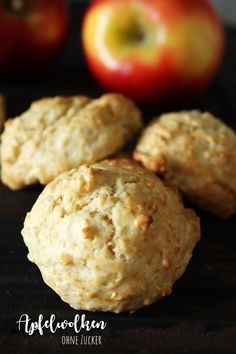 three biscuits sitting on top of a table next to an apple