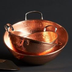 two copper pans sitting next to each other