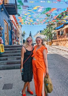 two women standing next to each other in front of colorful flags hanging from the ceiling