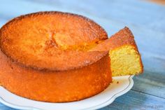 a yellow cake on a white plate with a piece missing from it's side