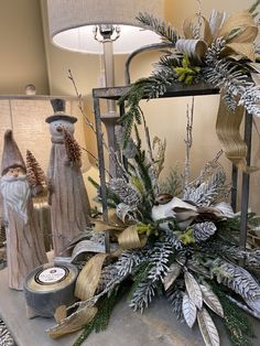 a christmas display with candles and ornaments on a table in front of a lamp shade