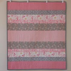 Have a baby girl on the way?  Need a baby shower gift?  Enjoy this quilt made using prints in pink, gray, and white curated from a number of great fabric collections.  There are florals, dots, checks, leaves, and geometric patterns.  The quilting pattern is a series of vertical wavy lines to complement the straight vertical seams. This quilt measures 33" by 38".  It will be perfect for use in a crib or stroller as well as a play mat.  The fabrics, batting, and threads used are all 100% cotton. Quilt Baby Blanket, Quilted Baby Blanket, Quilt Baby, Wavy Lines, Fabric Collections, Blanket Baby, Shower Baby, Play Mat, Having A Baby