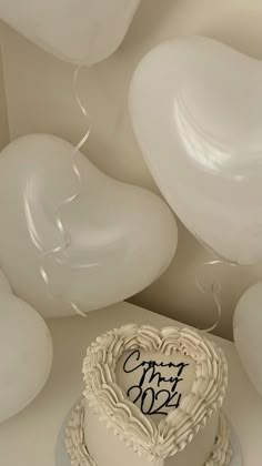 a heart shaped cake sitting on top of a table next to balloons and streamers