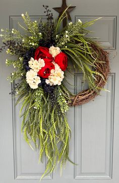 a wreath with red, white and black flowers hanging on a door