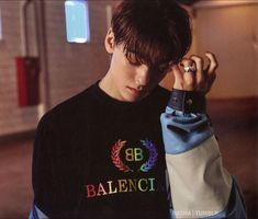 a young man is holding his hand to his ear while wearing a black shirt with the word balance on it