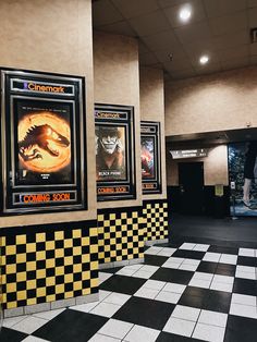 the movie posters are hanging on the wall in the building's lobby area, with black and yellow checkered flooring