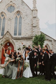 a group of people standing in front of a church with their arms in the air