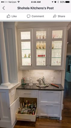 a kitchen with white cabinets and black counter tops, filled with wine glasses in the bottom drawer