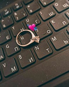 a pair of scissors sitting on top of a laptop keyboard with two hearts attached to it