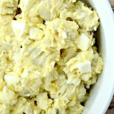 a white bowl filled with mashed potatoes on top of a wooden table