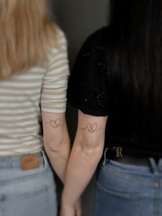 two women with matching tattoos on their arms