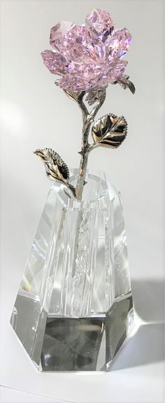 a crystal flower with two leaves in it sitting on a table next to a white background