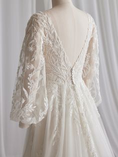 the back of a wedding dress with white lace on it and sleeves that are open