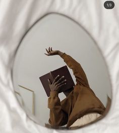 a woman reading a book in front of a mirror