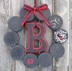 a wreath made out of black and red rocks with the letter b painted on it