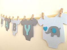 baby shower decorations hanging on clothesline with blue and gray elephant onesuits,