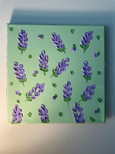 a painting with purple flowers on a green background is hanging on the wall in front of a white wall