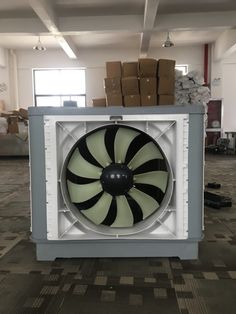 an industrial fan sitting in the middle of a room with cardboard boxes on the floor