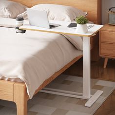 a laptop computer sitting on top of a bed next to a night stand with a plant