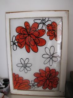 an old window with red flowers painted on the glass in front of it and some other items nearby