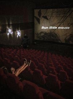 a woman laying on the floor in front of a movie screen with her feet up