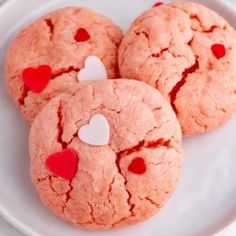 three heart shaped cookies on a white plate