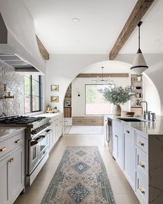 a large kitchen with white cabinets and an area rug on the floor in front of it