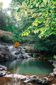 a man riding a yellow raft down a river surrounded by rocks and greenery on a sunny day