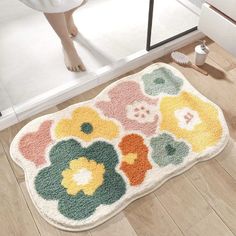 a bathroom rug with colorful flowers on it and a person standing in the mirror behind it