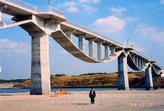 a man is standing in front of a large bridge that has been built over water