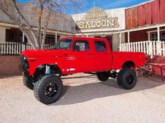 a red truck parked in front of a building with a sign that says saloon on it