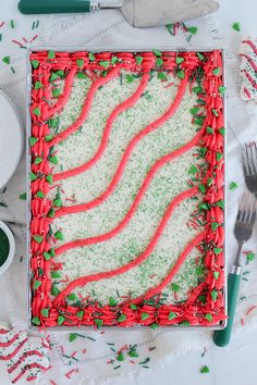 a red and green cake sitting on top of a table next to utensils