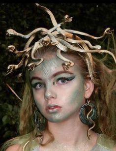 a woman with white makeup and snakes on her head