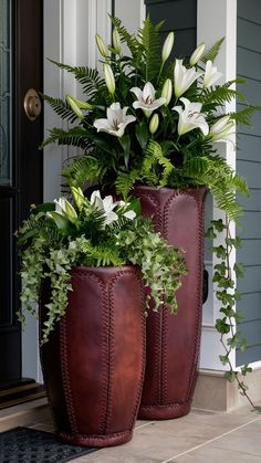 two large vases with plants in them sitting on the front step of a house