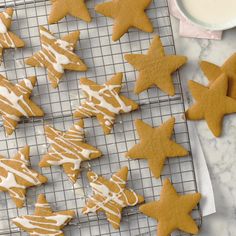 cookies decorated with icing sitting on a cooling rack next to a cup of milk